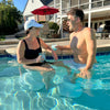 Man and woman enjoying drinks while seated on in-pool bar stools in residential backyard pool