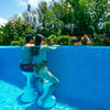 Couple using submersible pool stools for instant underwater seating along pool wall