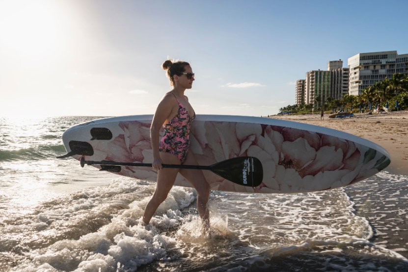 floral inflatable paddleboard - walking out of ocean