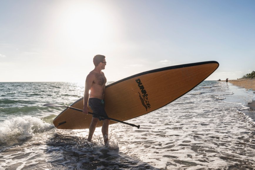 natural wood inflatable paddleboard - standing in surf
